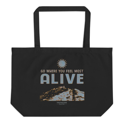 Black organic tote bag with motivational quote 'Go where you feel most alive' and sun graphic on a white background