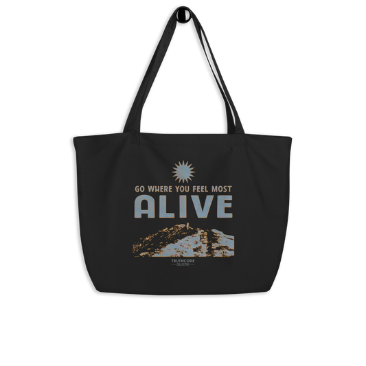 Black organic tote bag with motivational quote 'Go where you feel most alive' and nature graphic on a white background