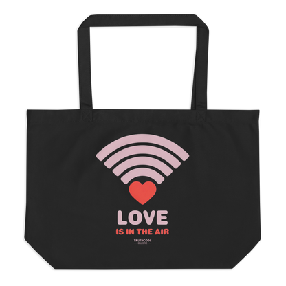 Black organic tote bag with pink heart wifi graphic design and text 'LOVE IS IN THE AIR' on a white background