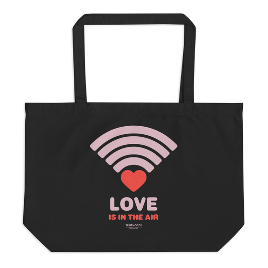 Black organic tote bag with pink heart wifi graphic design and text 'LOVE IS IN THE AIR' on a white background