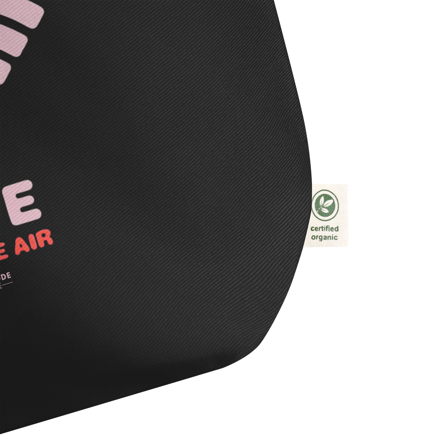 Corner of black tote bag showing a certified organic label on a white background