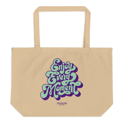 Beige organic tote bag with 'Enjoy Every Moment' text in purple and green on a white background