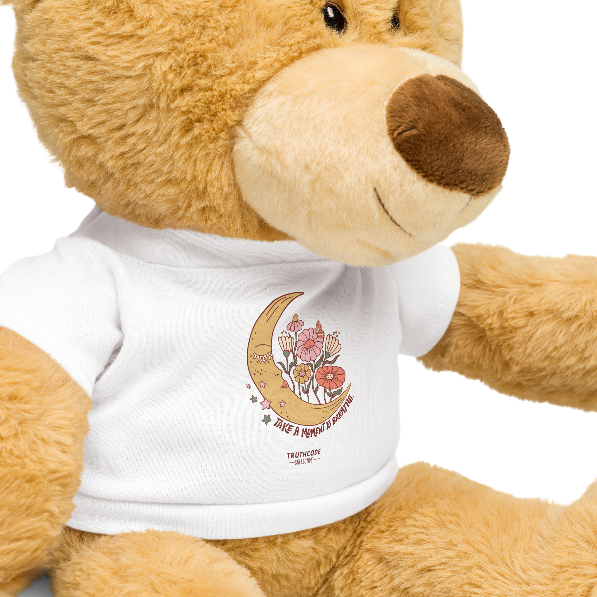 Teddy bear wearing a white t-shirt with a moon and floral design and text 'Take a moment to breathe' 