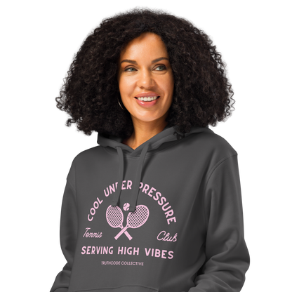 Woman wearing dark gray organic hoodie with pink and white text 'Cool under pressure, serving high vibes' and tennis graphics on a white background