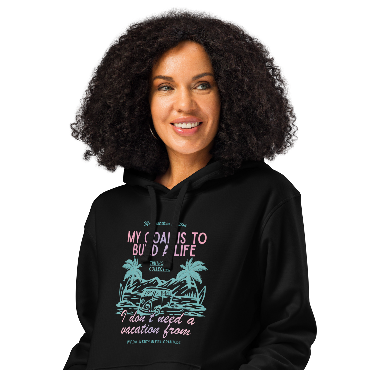 Woman wearing black organic hoodie with tropical graphic and text 'My goal is to build a life I don't need a vacation from' on a white background