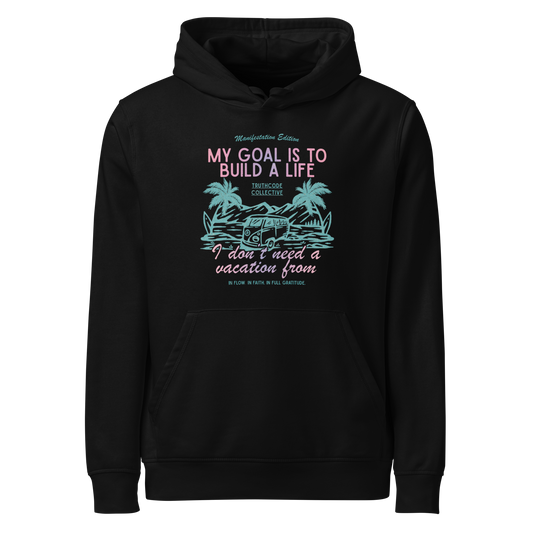 Black organic hoodie with tropical graphic and text 'My goal is to build a life I don't need a vacation from' on a white background