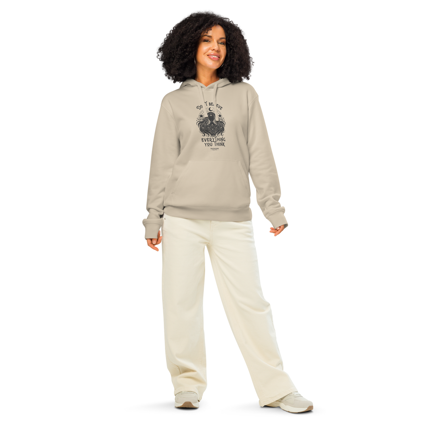 Woman wearing beige organic hoodie with cosmic woman graphic design and text 'Don't believe everything you think' on a white background