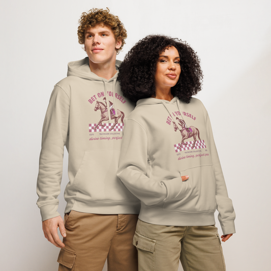Models wearing beige organic hoodie with graphic design of race horse and jockey and text 'Bet on yourself' on a plain background