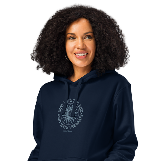 Womean wearing navy blue organic hoodie with a circular sun/moon design and text 'Rise with the sun, rest with the moon' on a white background