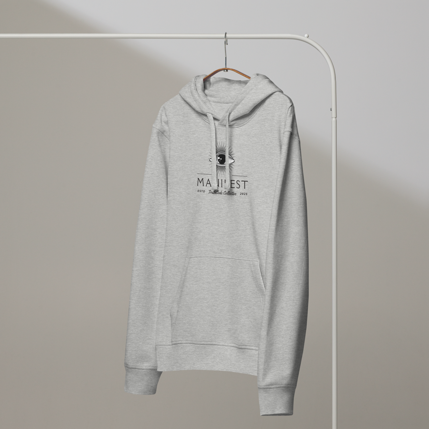 Gray organic hoodie with text 'Manifest' and graphic design of an eye on a hanger with a gray wall background