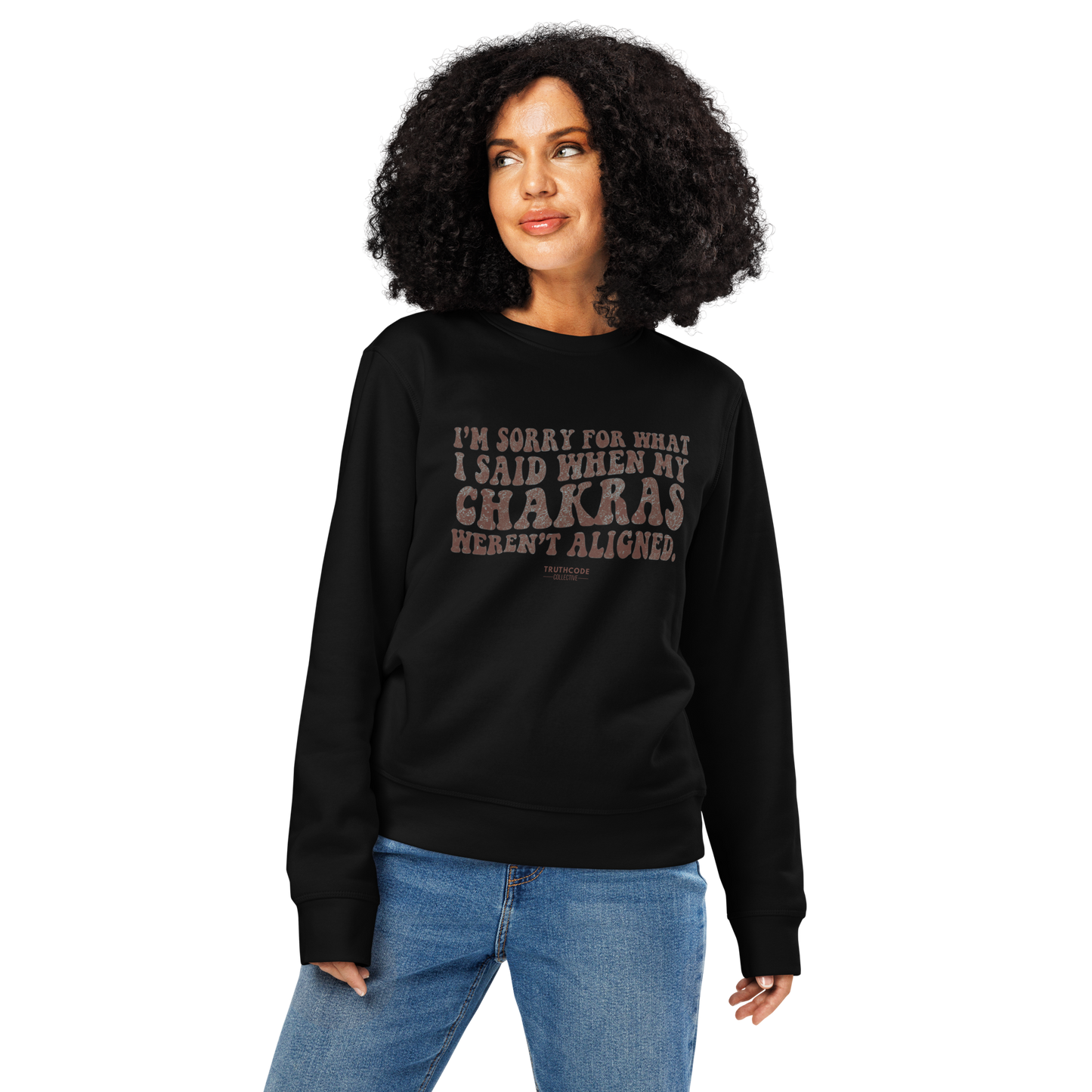 Woman wearing black organic sweatshirt with humorous text design 'I'm sorry for what I said when my chakras weren't aligned' on a white background