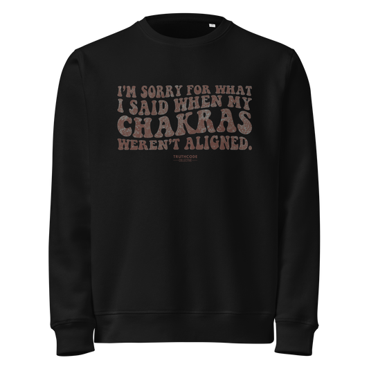 Black organic sweatshirt with humorous text design 'I'm sorry for what I said when my chakras weren't aligned' on a white background