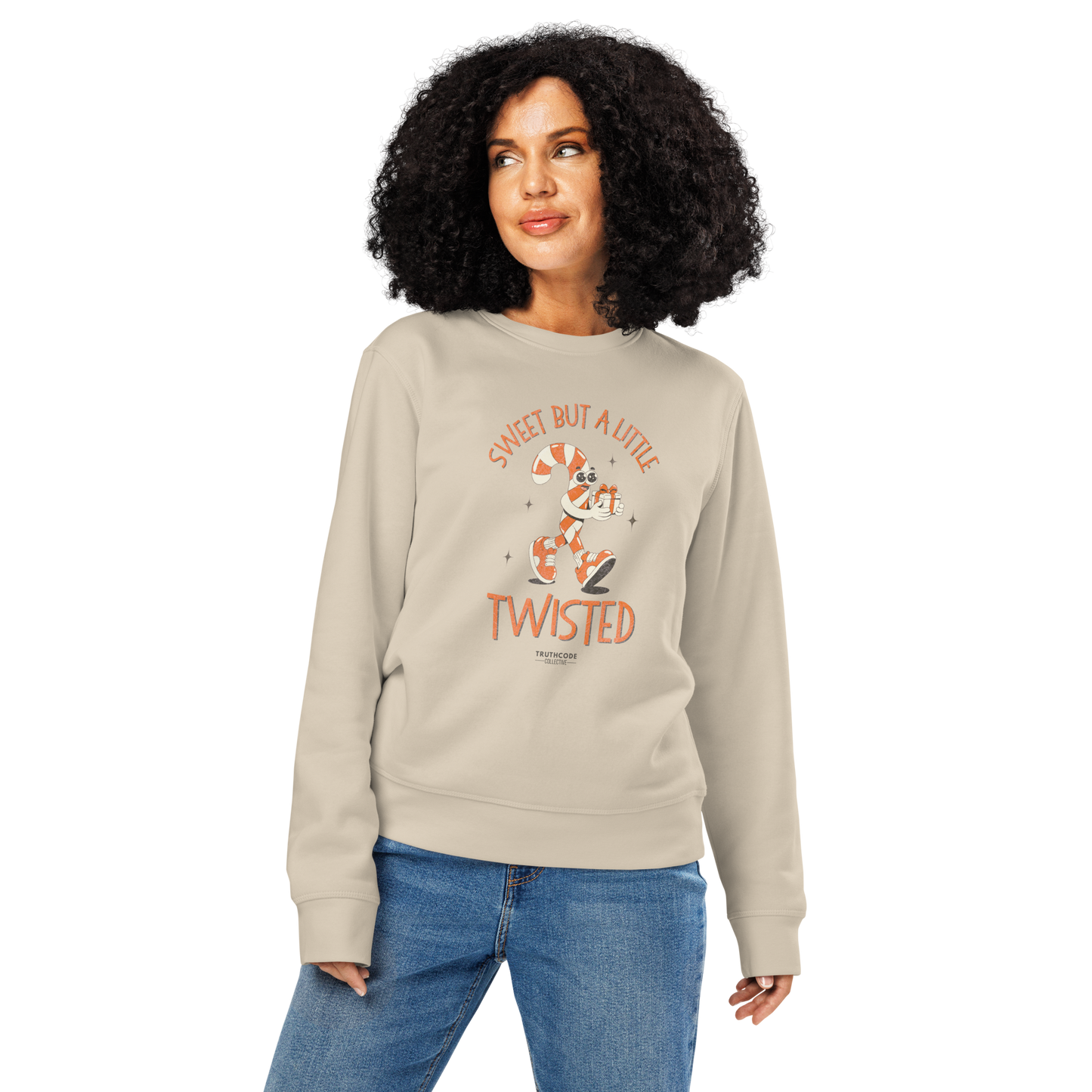 Woman wearing a beige organic sweatshirt with a candy cane cartoon graphic design and text 'Sweet but a little twisted' on a white background