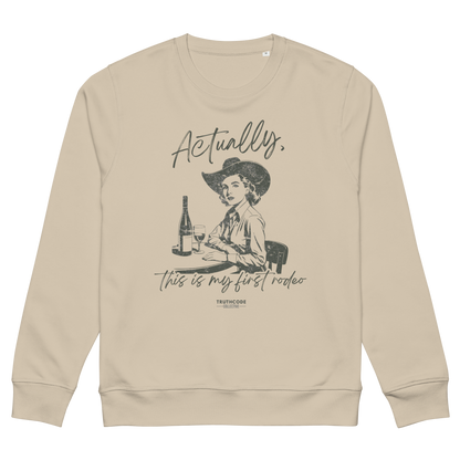 Beige organic sweatshirt with a vintage style graphic of a woman in a cowboy hat and text 'Actually, this is my first rodeo' on a white background