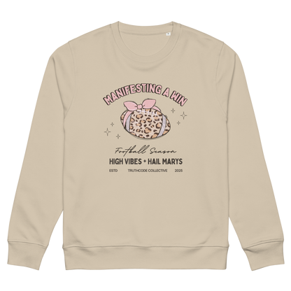 Beige organic sweatshirt with girly football graphic design and text 'Manifesting a win, high vibes and hail marys' on a white background