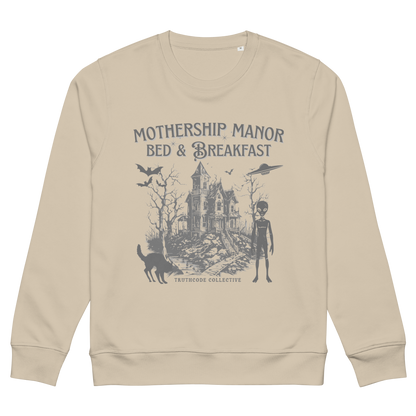 Beige organic sweatshirt with a graphic design of a haunted house, alien, and spaceship, with text 'Mothership Manor Bed & Breakfast' on a white background