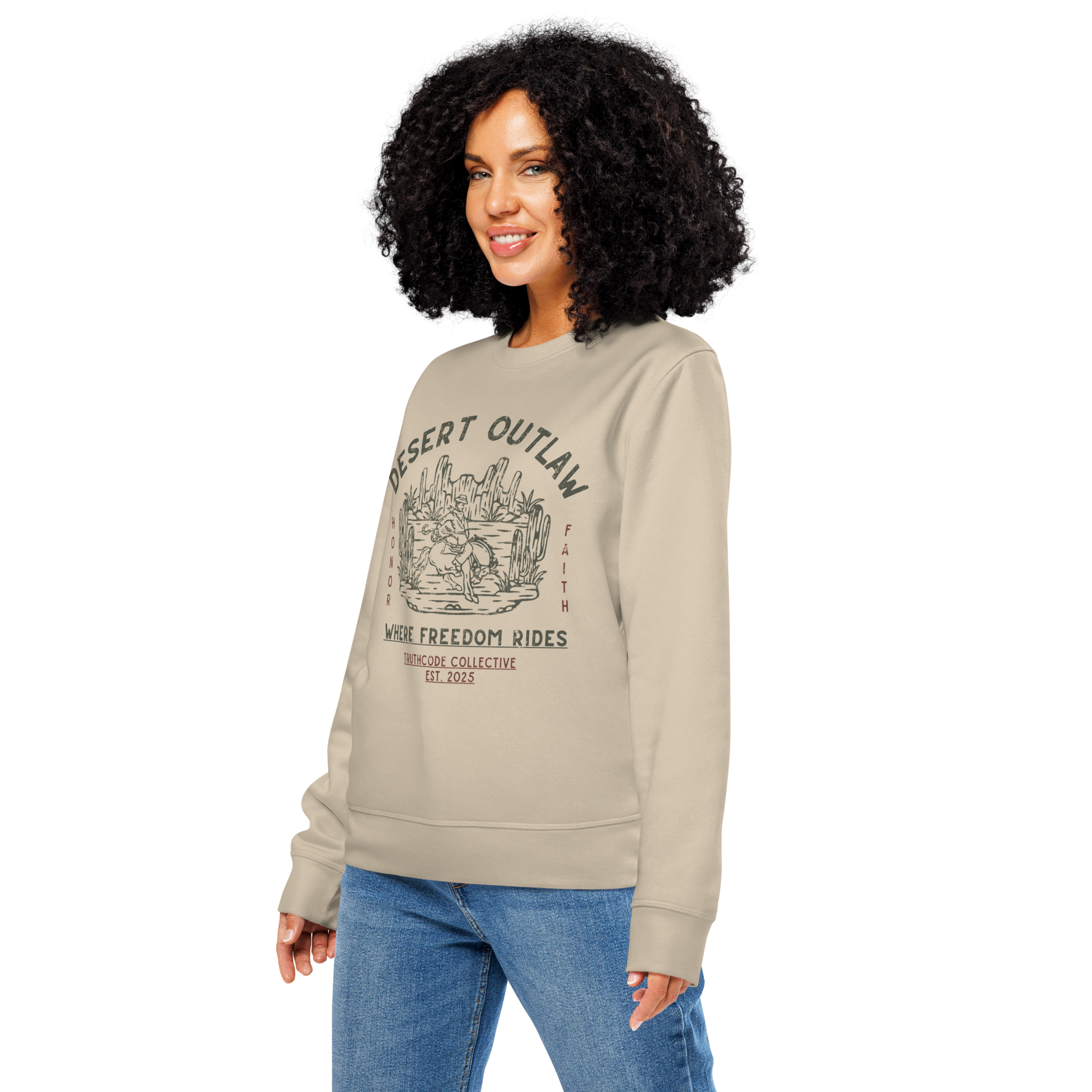 Woman wearing beige organic sweatshirt with 'Desert Outlaw, where freedom rides' text and graphic design of cowboy riding a broco in the desert, on a white background