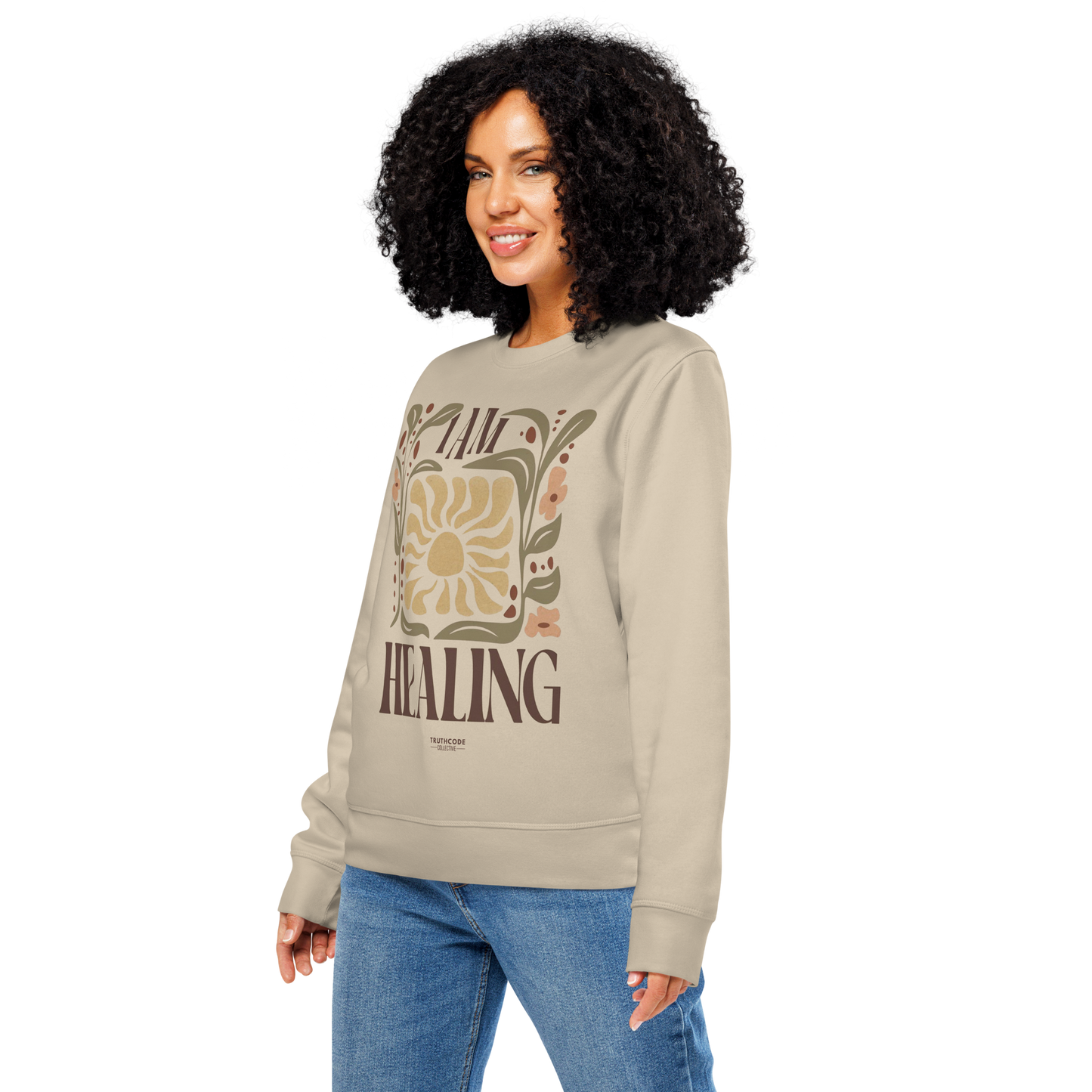 Woman wearing beige organic sweatshirt with 'I AM HEALING' text and sun and plants design on a white background