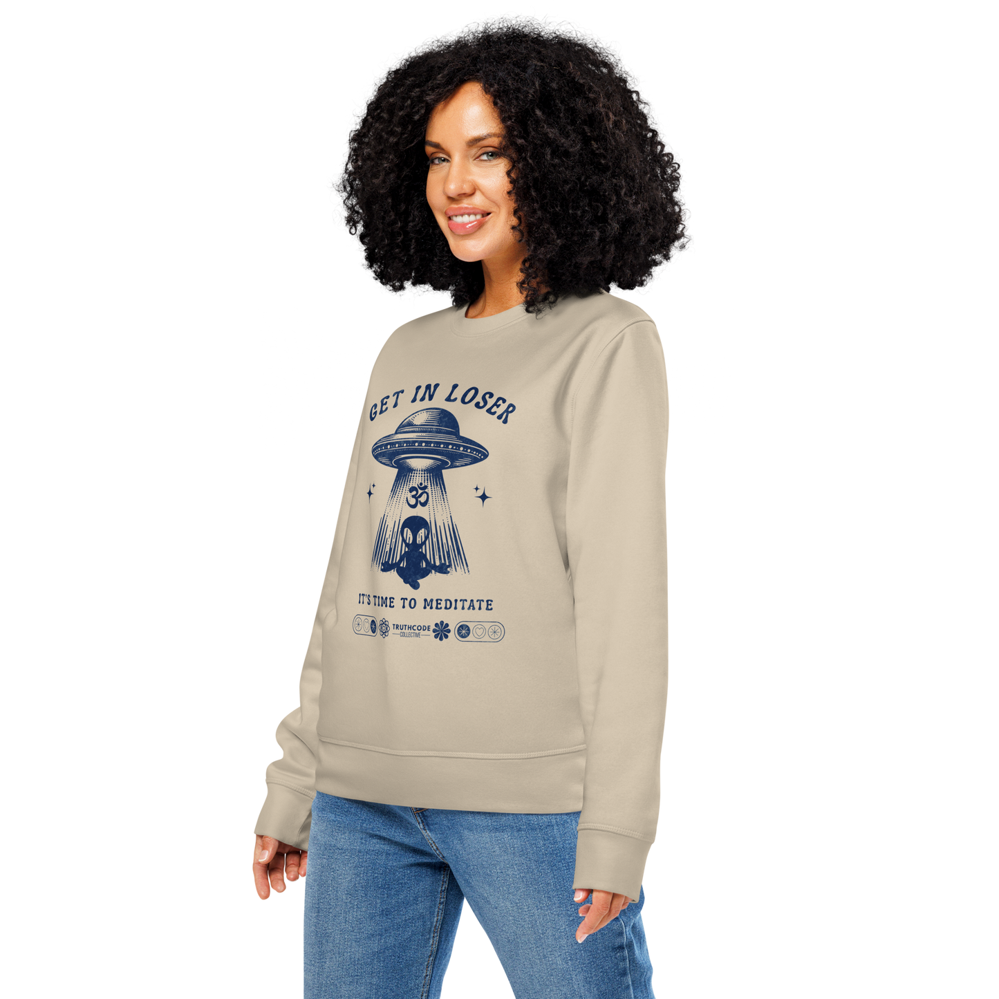 Woman wearing beige organic sweatshirt with alien and spaceship graphic and text 'Get in loser, it's time to meditate' on a white background