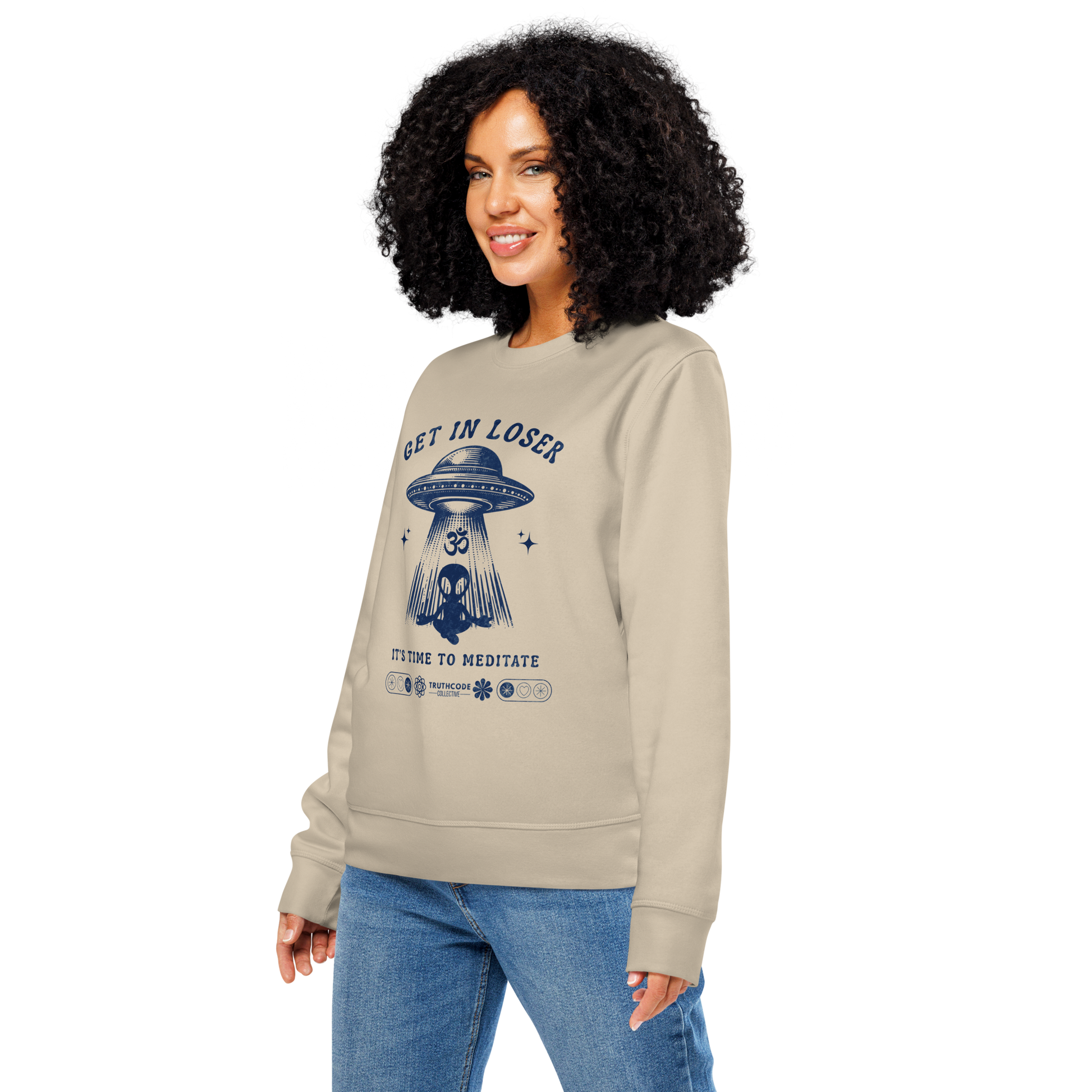 Woman wearing beige organic sweatshirt with alien and spaceship graphic and text 'Get in loser, it's time to meditate' on a white background