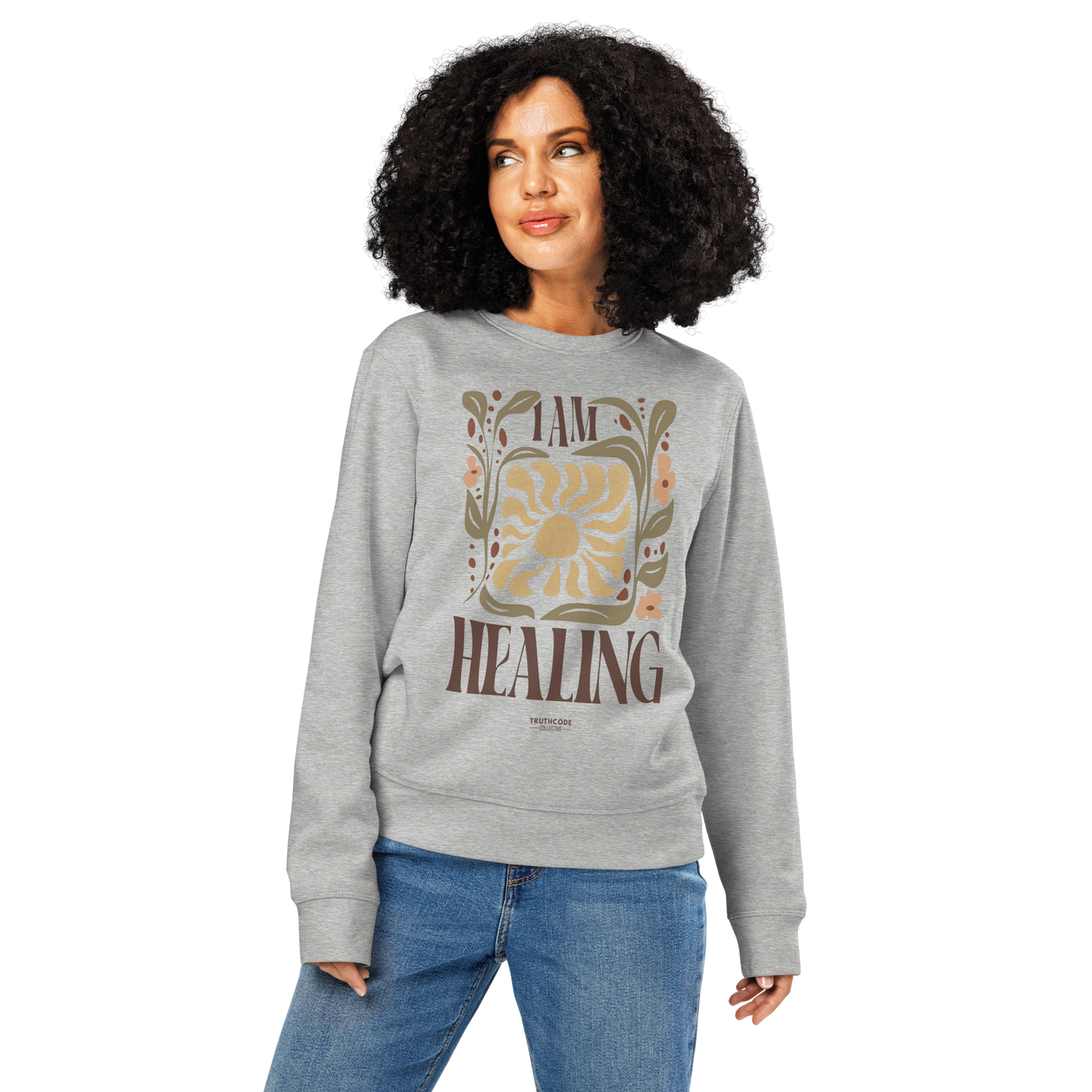 Woman wearing gray organic sweatshirt with 'I AM HEALING' text and floral design on a white background