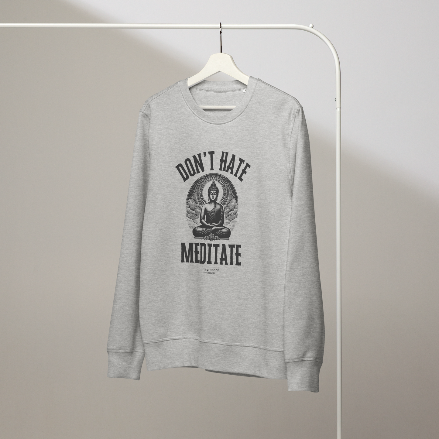 Gray organic sweatshirt with Buddha graphic and 'Don't Hate Meditate' text on a white hanger with a gray wall background