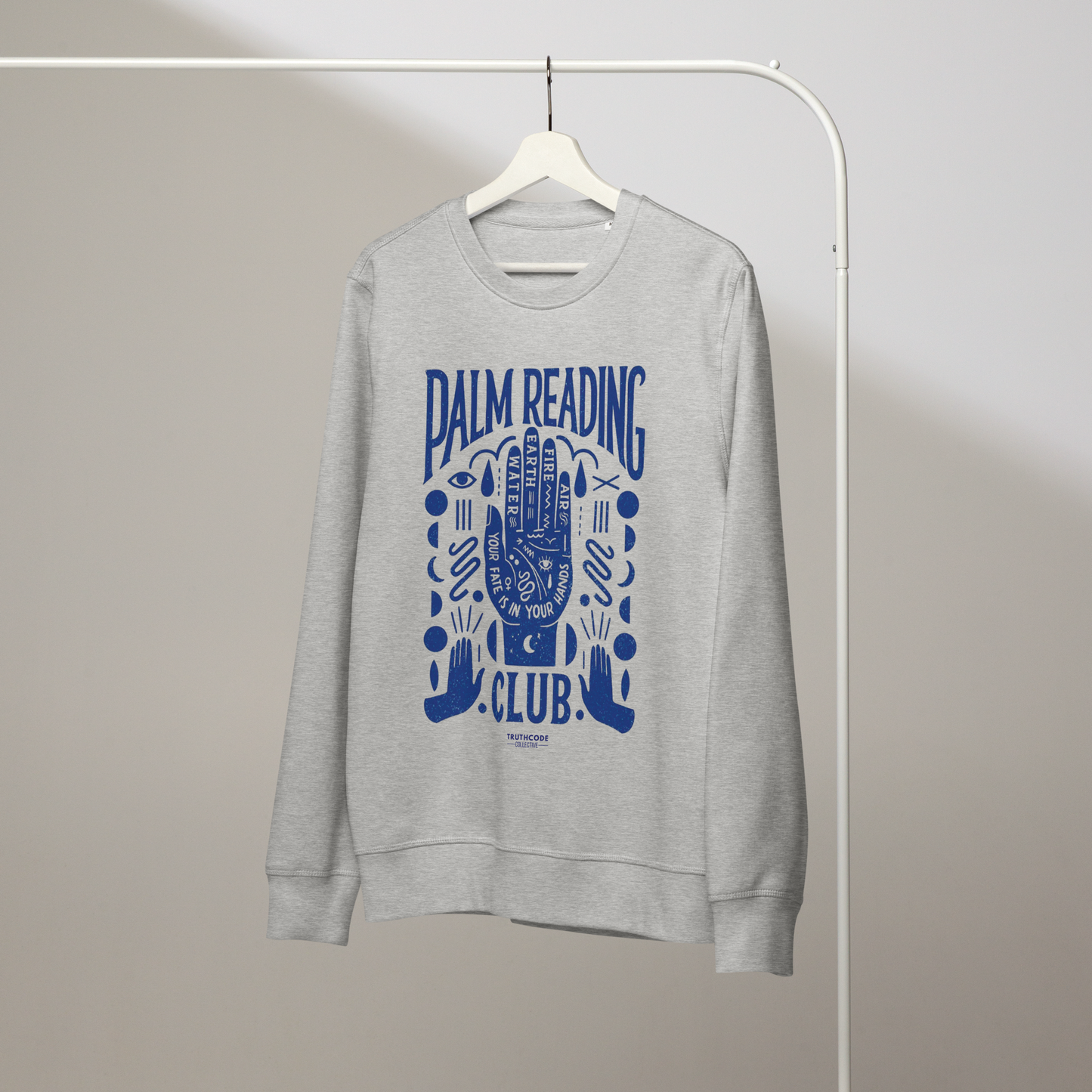 Gray organic sweatshirt with blue palm reading design and text 'Palm reading club' on a white hanger with a gray wall background