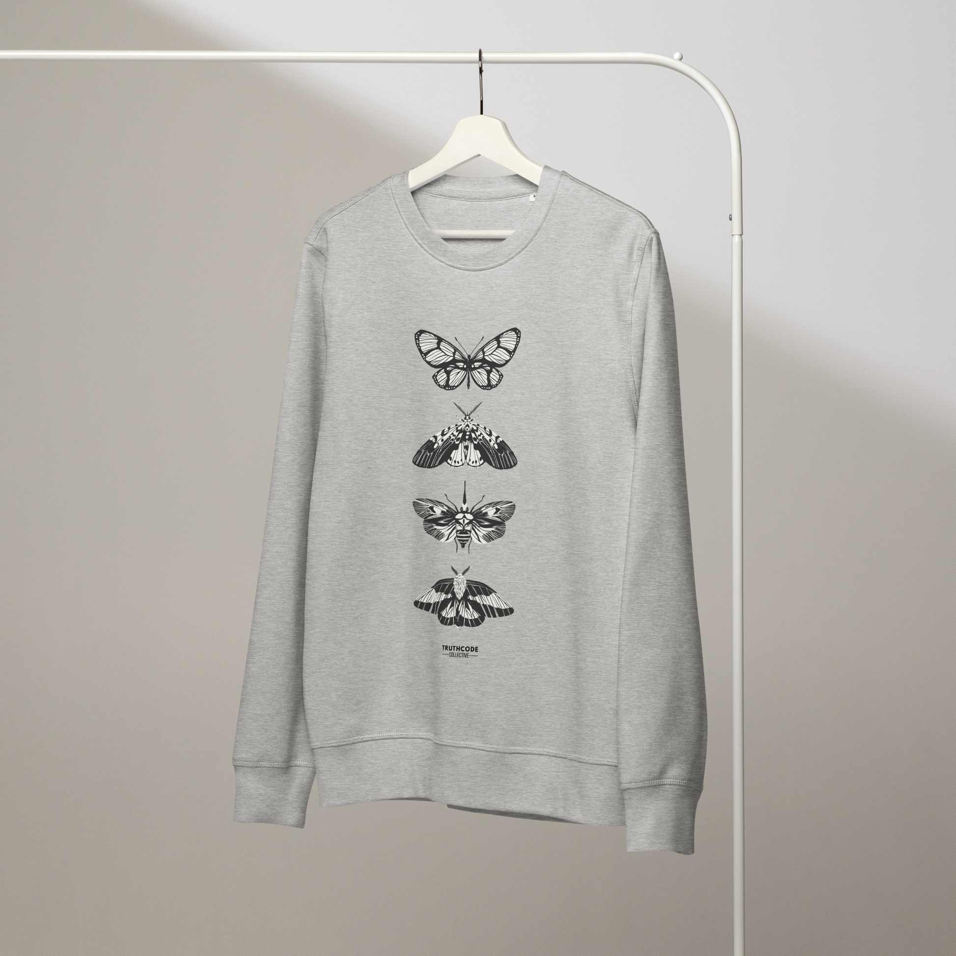 Gray organic sweatshirt with various butterfly designs on a white hanger with a gray wall background