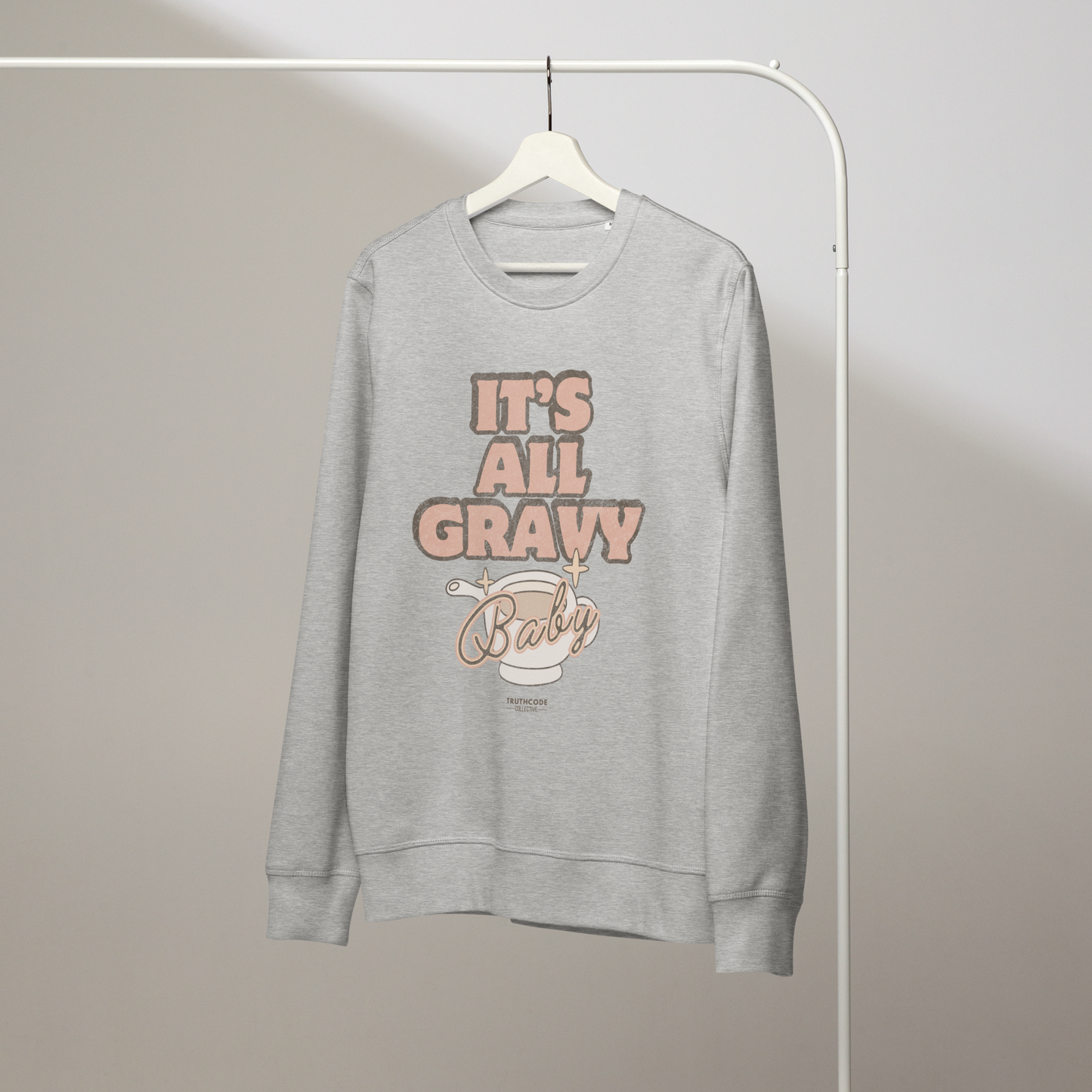 Gray organic sweatshirt with 'It's All Gravy Baby' text and graphic design of a gravy boat on a white hanger with a gray wall background