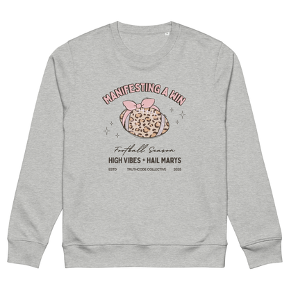 Gray organic sweatshirt with girly football graphic design and text 'Manifesting a win, high vibes and hail marys' on a white background