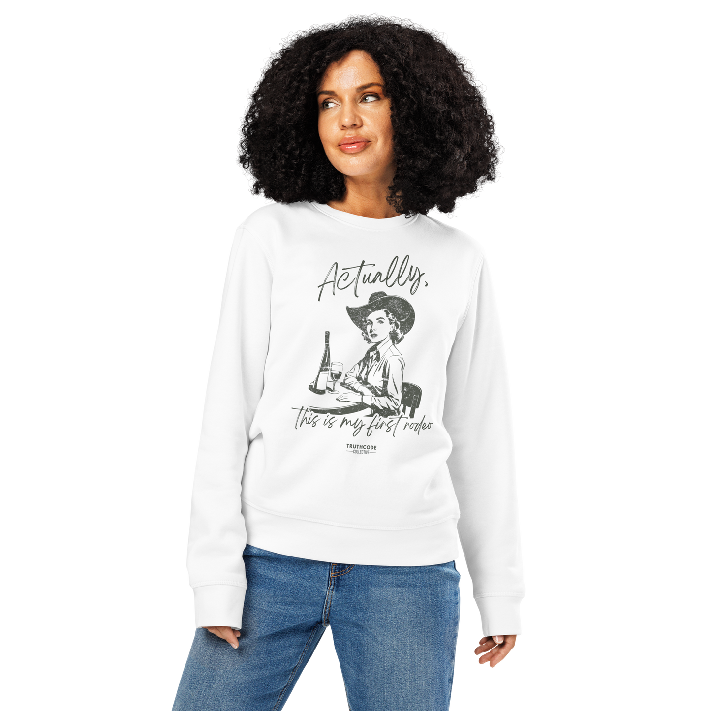 Woman wearing white organic sweatshirt with vintage graphic of a woman in a cowboy hat and text 'Actually, this is my first rodeo' on a white background
