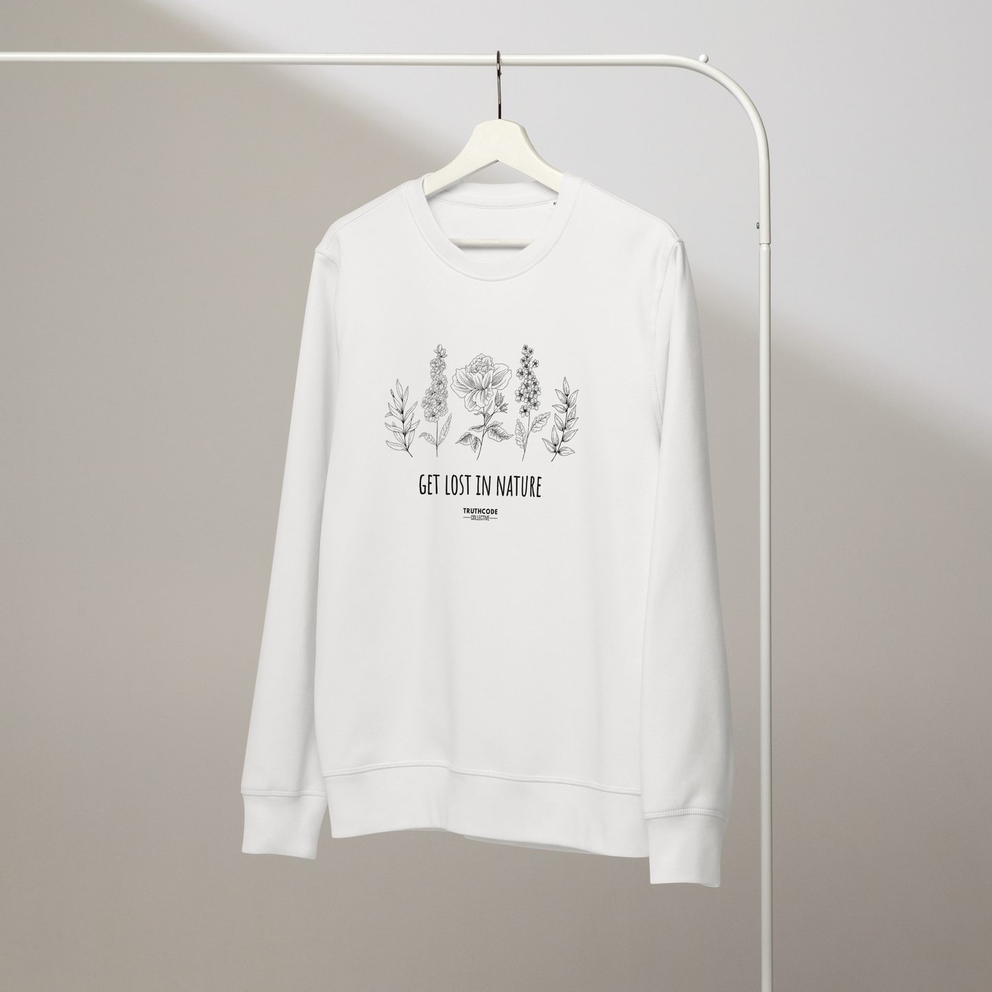 White organic sweatshirt with floral stems design and text reading 'Get lost in nature' on a hanger with a gray wall background