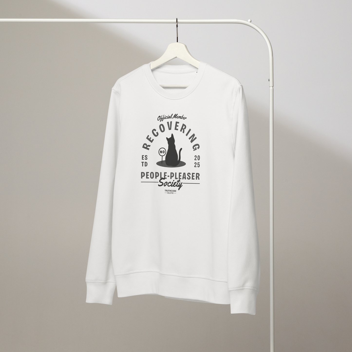White organic sweatshirt with a lighthearted design about a recovering people pleaser, featuring a cat silhouette on a white hanger with a gray wall background