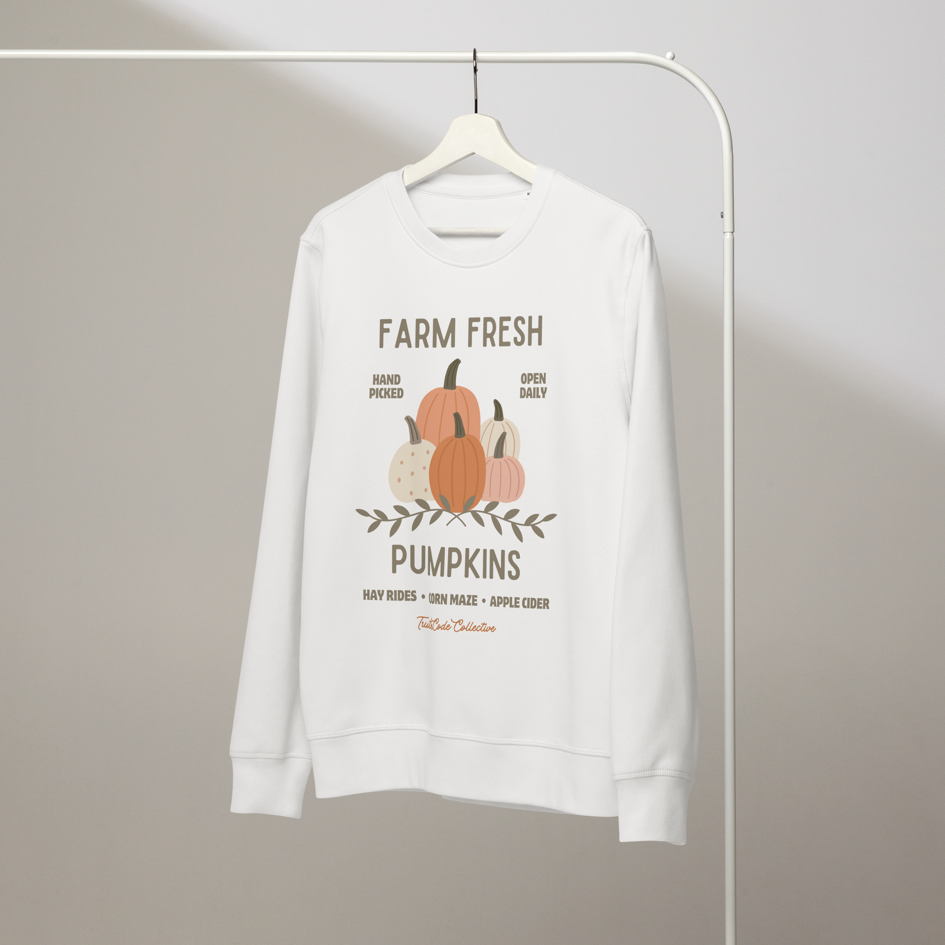 White organic sweatshirt with 'Farm Fresh Pumpkins' text and pumpkin graphic design on a white hanger with a gray wall background
