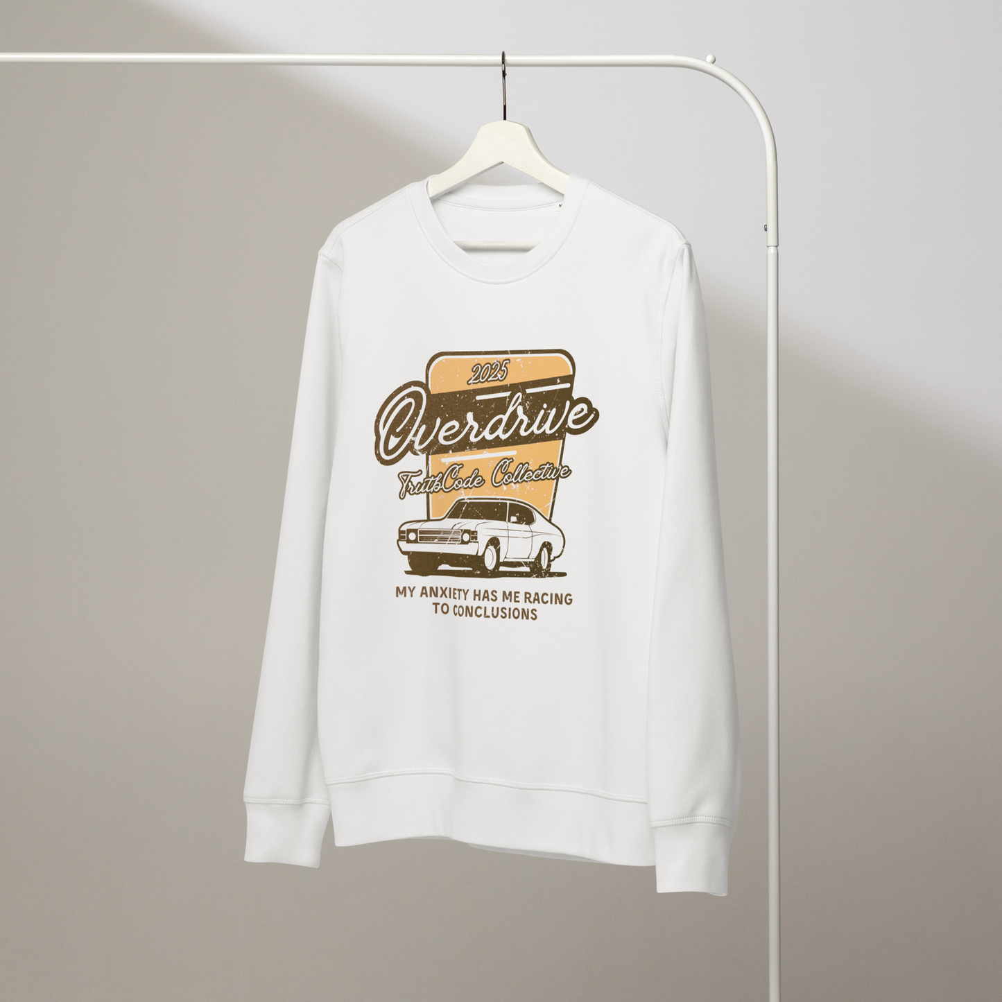 White organic sweatshirt with a vintage graphic design of a car and text 'Overdrive, my anxiety has me racing to conclusions' on a white hanger with a gray wall background