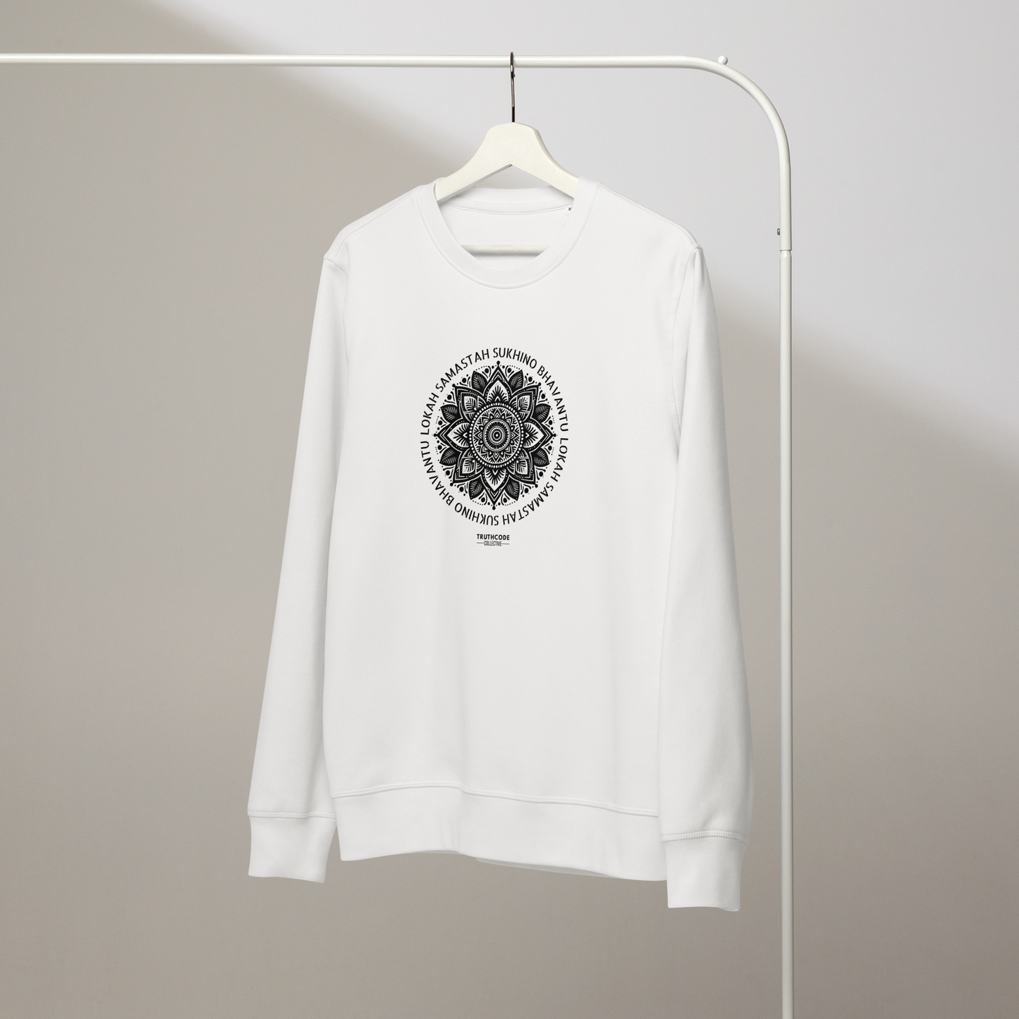 White organic sweatshirt with a black mandala design and text on a white hanger with a gray wall background