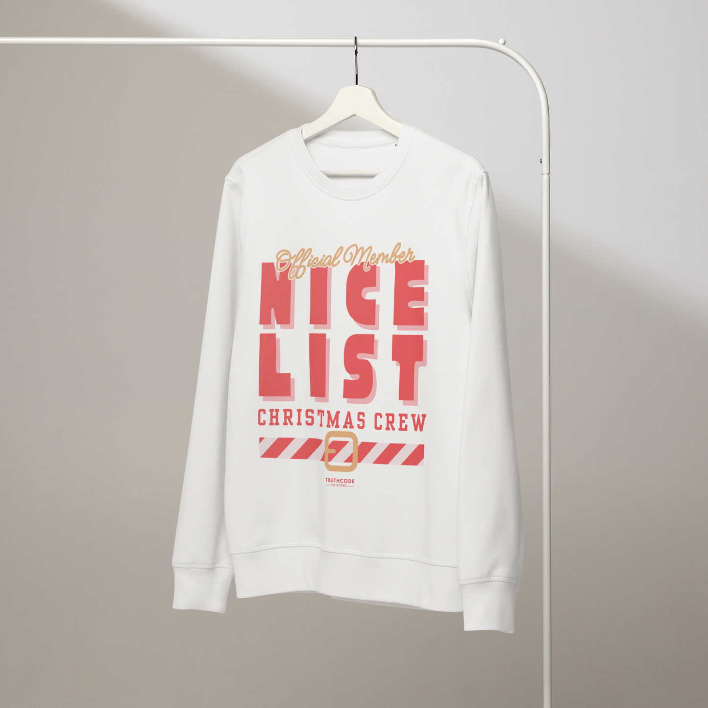 White organic sweatshirt with text 'Official member, nice list Christmas crew' with a holiday belt graphic on a hanger with a gray wall background