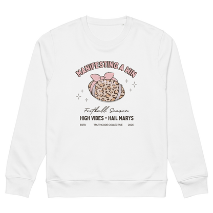 White organic sweatshirt with girly football graphic design and text 'Manifesting a win, high vibes and hail marys' on a white background