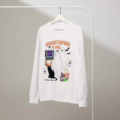 White organic sweatshirt with Halloween-themed design featuring a ghost, black cat, TV, and popcorn and text 'Spooky movies and chill' on a hanger with a gray wall background