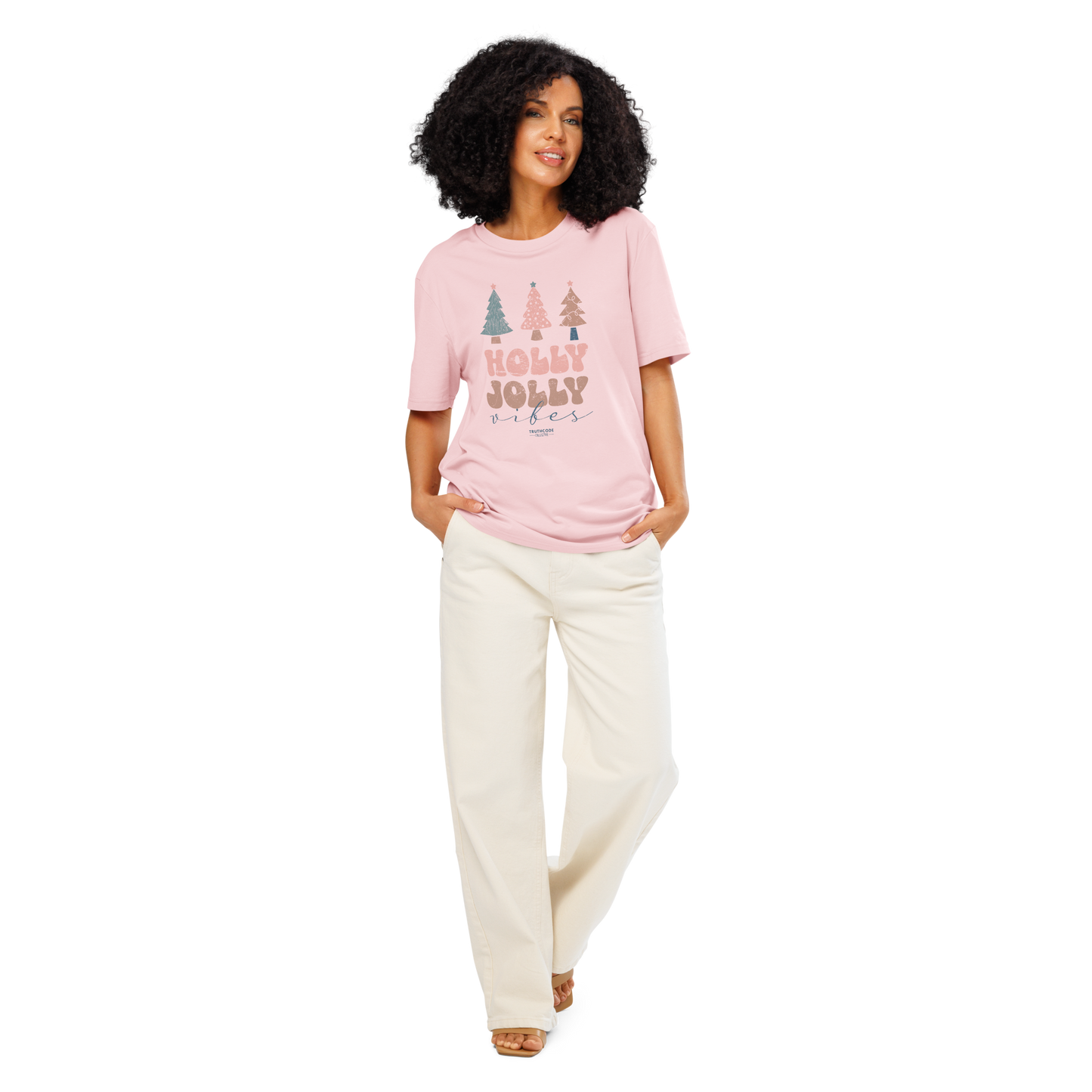 Woman wearing a pink 'Merry Jolly Vibes' t-shirt and white pants on a white background