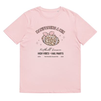 Pink organic t-shirt with girly football graphic design and text 'Manifesting a win, high vibes and hail marys' on a white background
