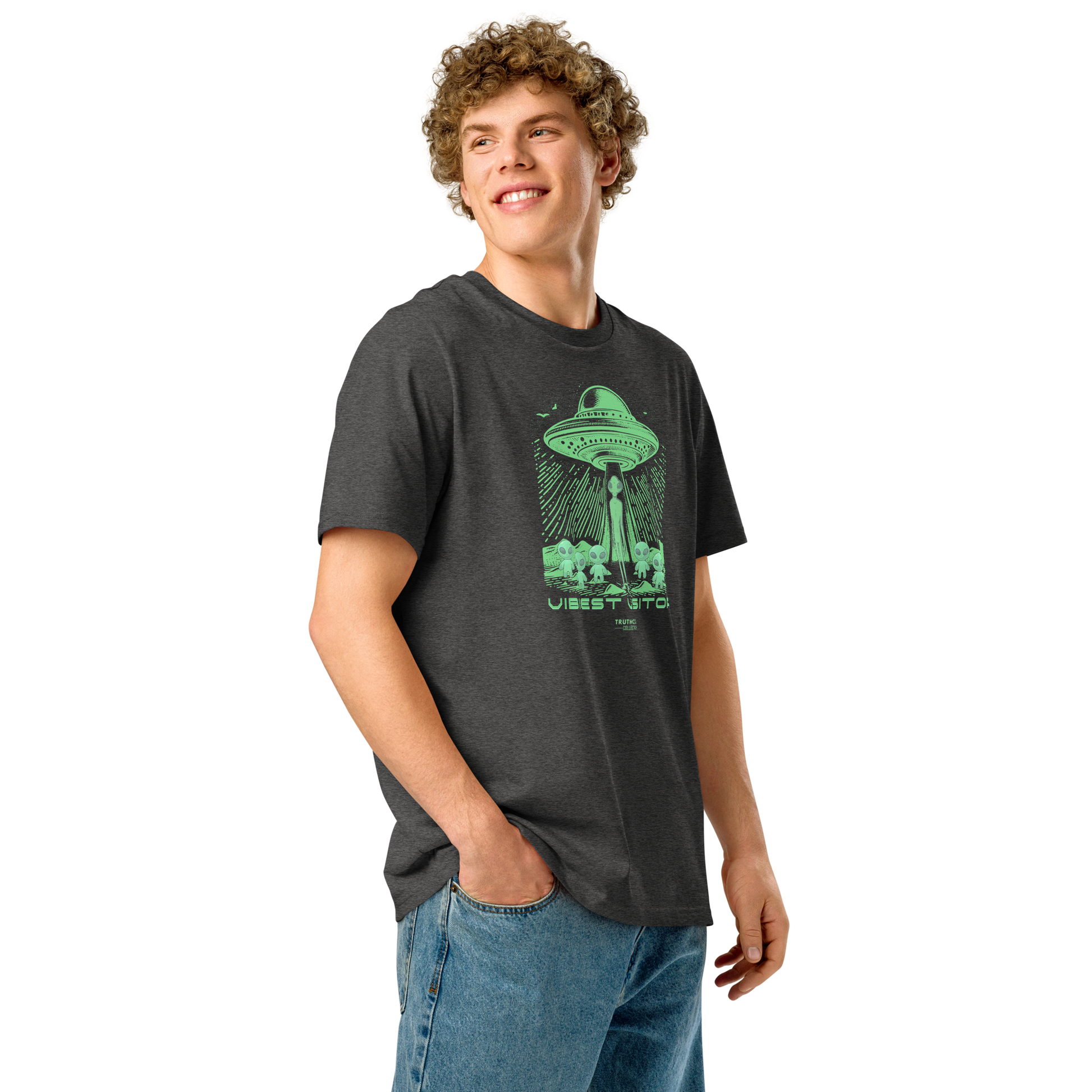 Guy wearing dark gray organic t-shirt with green alien abduction graphic and text 'Vibiest visitors' on a white background