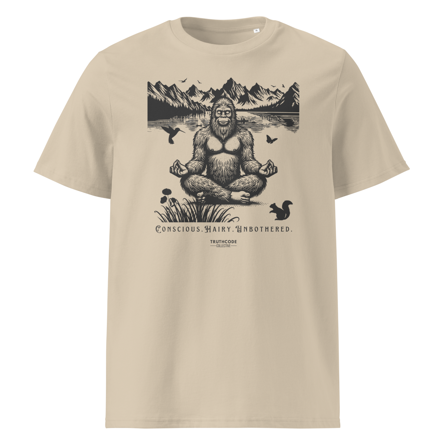 Beige organic t-shirt with a graphic of a meditating Sasquatch in a mountain setting and text reading 'Conscious, hairy, and unbothered' 