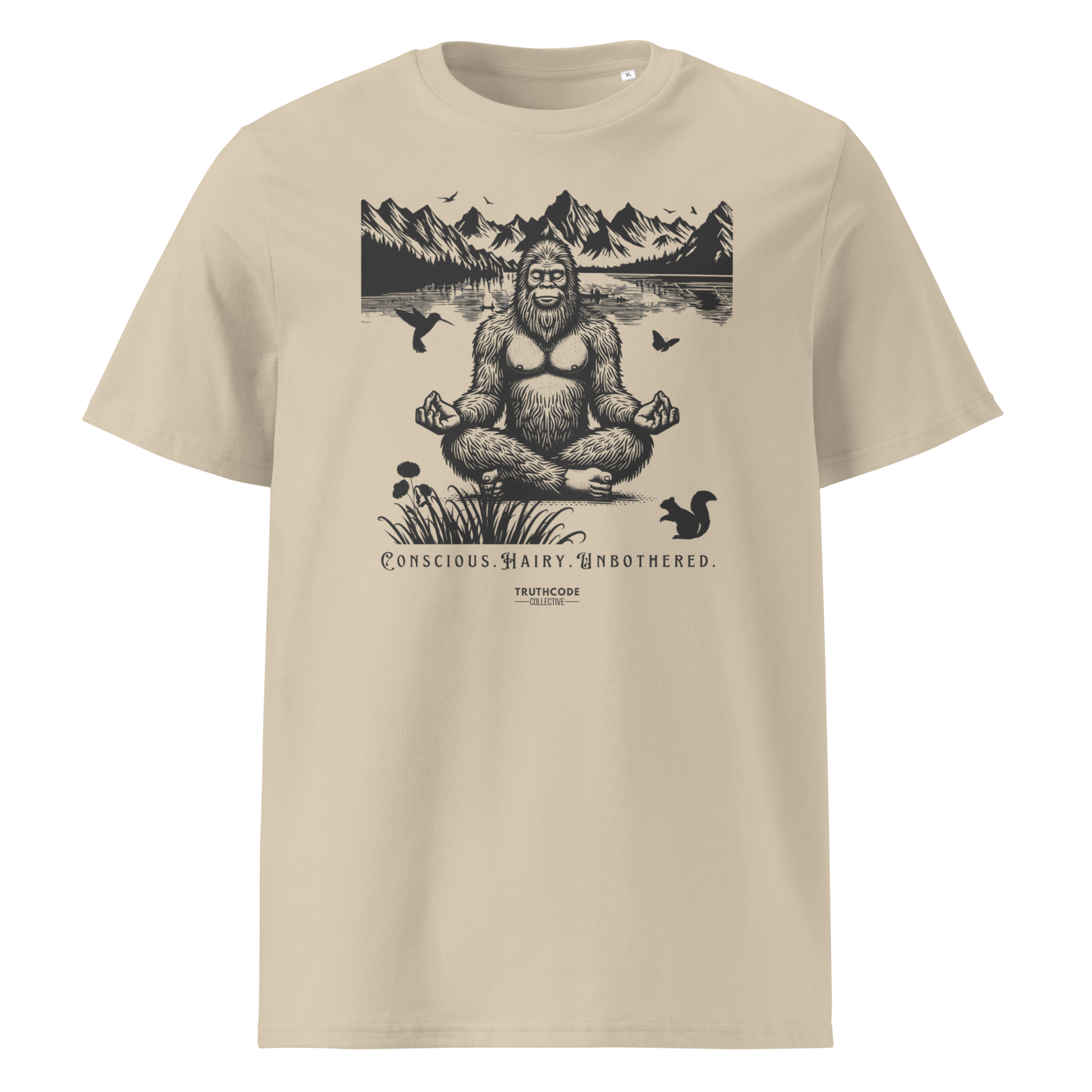 Beige organic t-shirt with a graphic of a meditating Sasquatch in a mountain setting and text reading 'Conscious, hairy, and unbothered' 
