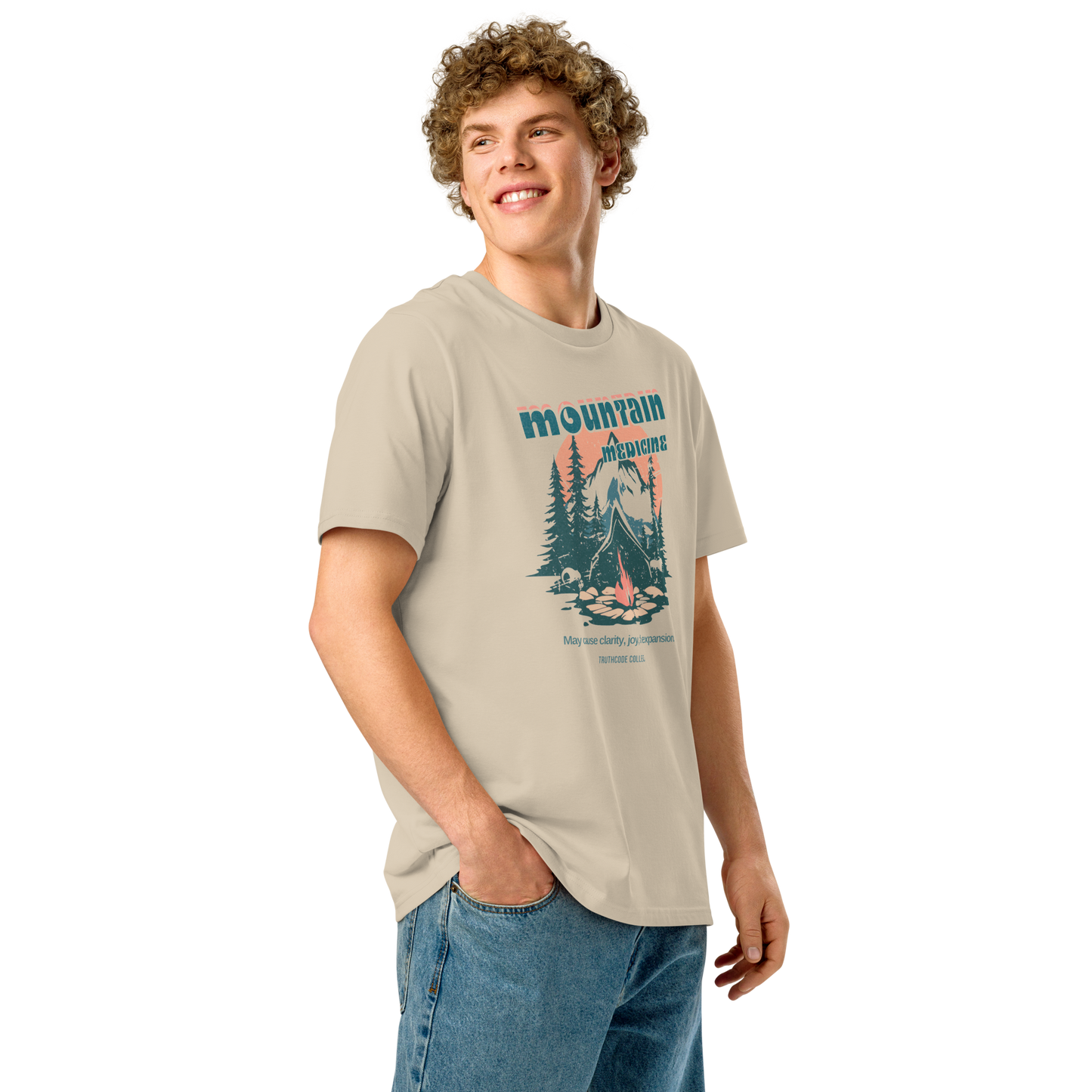 Guy wearing beige organic t-shirt with mountain and campfire graphic and 'Mountain Medicine' text on a white background