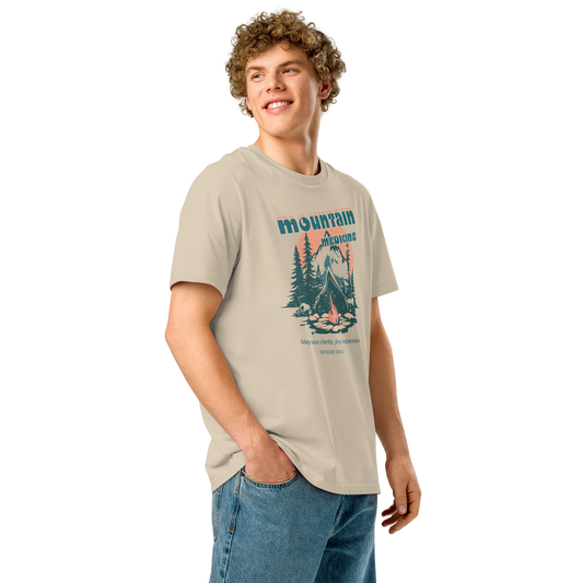 Guy wearing beige organic t-shirt with mountain and campfire graphic and 'Mountain Medicine' text on a white background