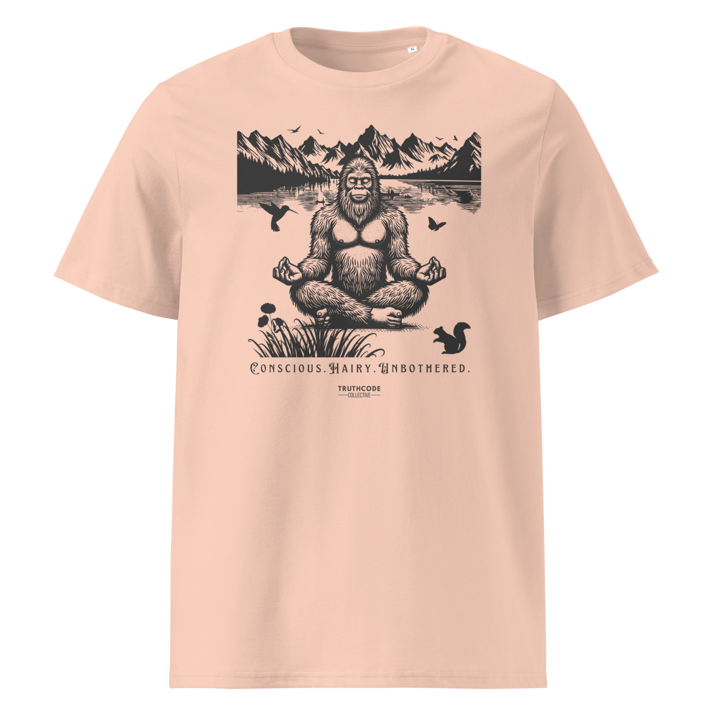 Pink organic t-shirt with a graphic of a meditating Sasquatch in a mountain setting and text reading 'Conscious, hairy, and unbothered' 