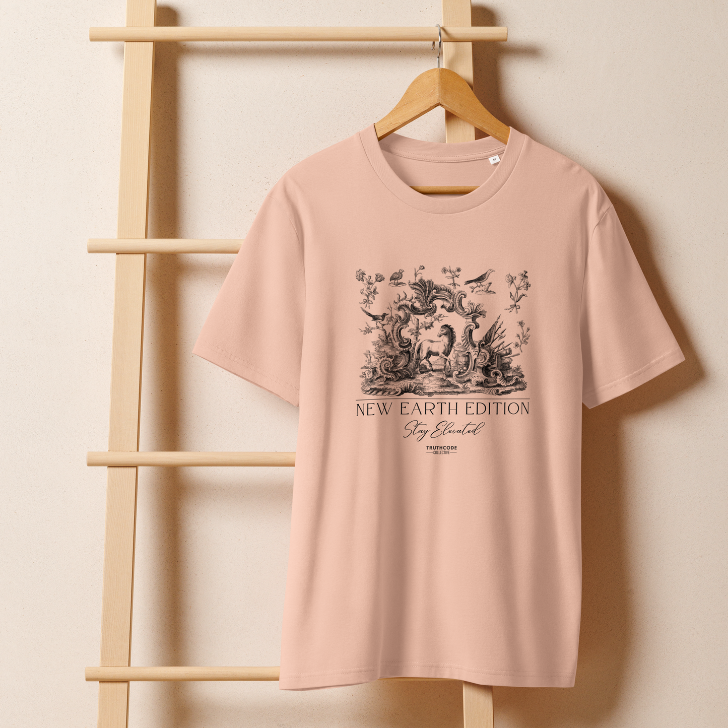 Peach organic t-shirt with nature and animals graphic design and text 'New earth edition, stay elevated' on a wooden hanger with a beige wall background