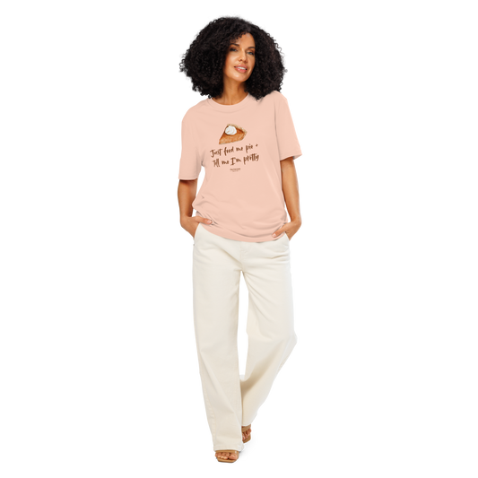 Woman wearing peach organic t-shirt with a pie graphic and text 'Just feed me pie + tell me I'm pretty' on a white background