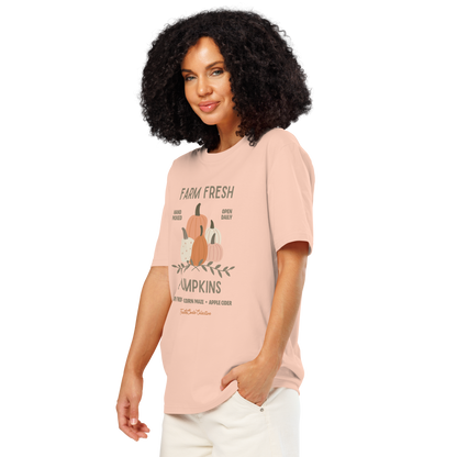 Woman wearing peach organic t-shirt with pumpkin graphic and text 'Farm fresh pumpkins, hay rides, corn maze, apple cider'  on a white background
